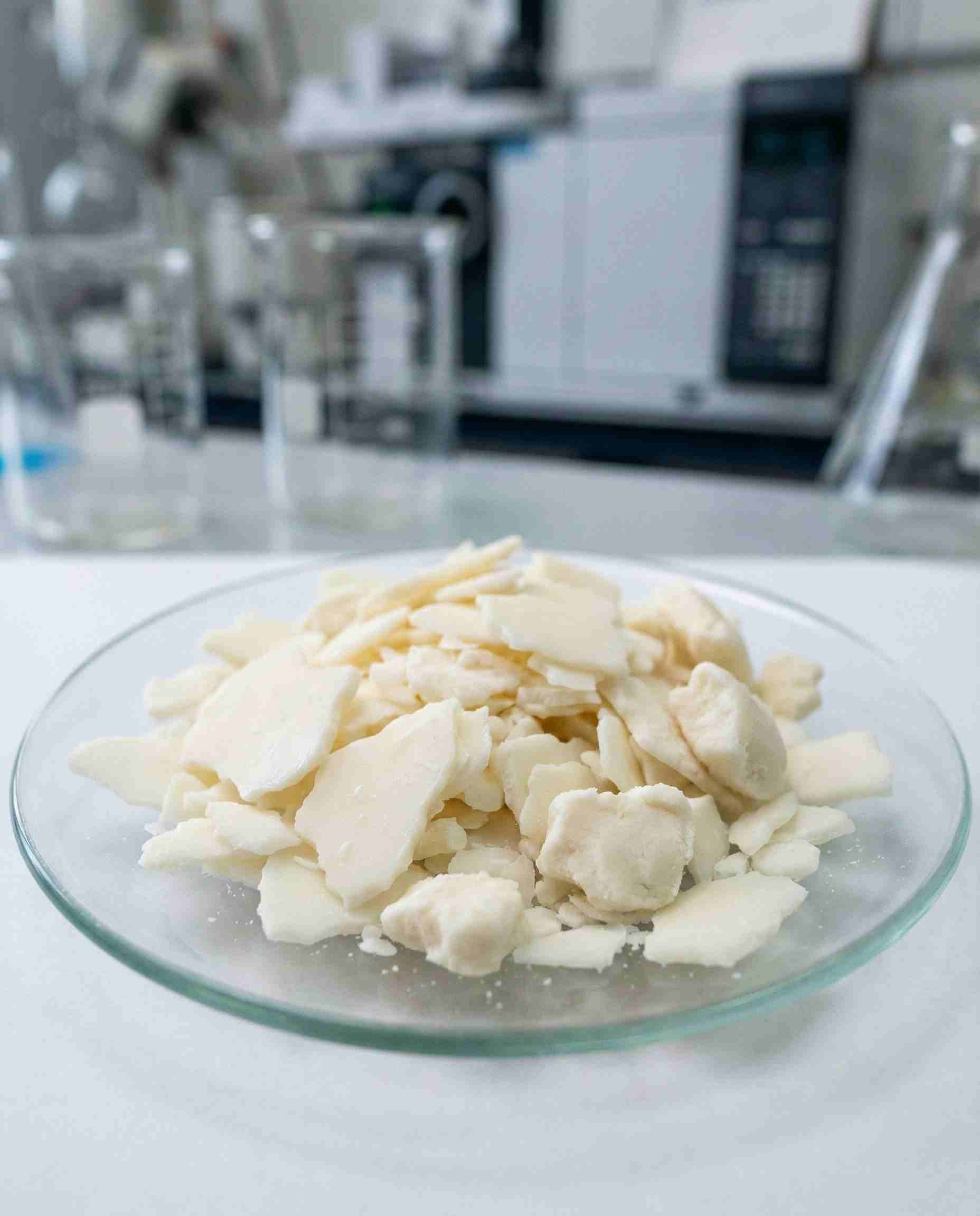 Solid waxy flakes of Polysorbate 61 surfactant, highlighting its solid physical state compared to liquid emulsifiers.